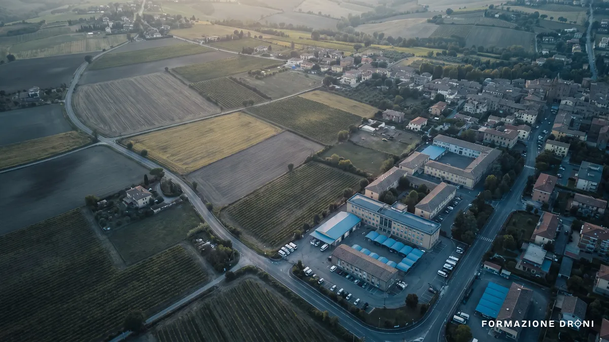 Veduta aerea di una cittadina italiana circondata da campi coltivati al tramonto
