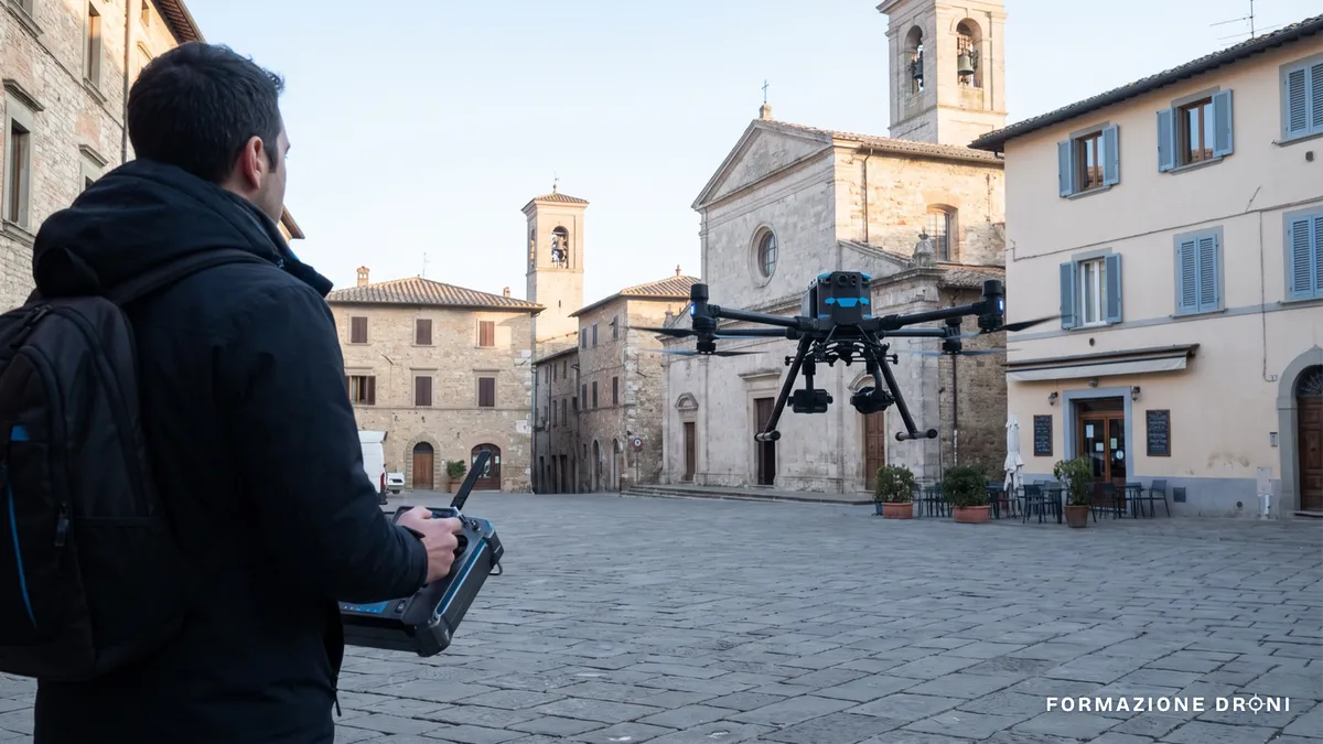 Drone in volo a bassa quota su una piazza con il pilota remoto a distanza di sicurezza